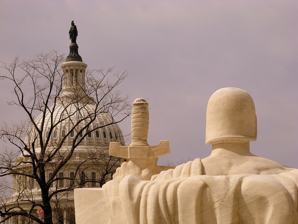 Statue outside the Supreme Court with the Capitol dome behind